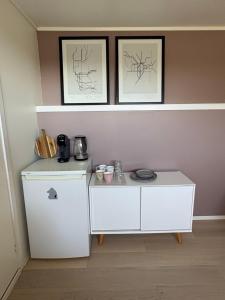 a small white cabinet with two pictures on the wall at Northern Suite in Tromsø