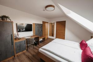 a bedroom with a bed and a desk with a television at Weingut Pugl in Leibnitz