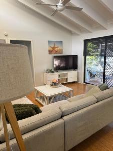 a living room with a couch and a tv at Frangipani in Shoal Bay