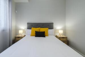 a bedroom with a large white bed with yellow pillows at Torrejón Suites 2 in Torrejón de Ardoz