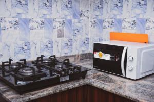 a microwave sitting on a counter next to a stove at Living Space Service Apartment in Mama