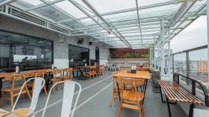 a restaurant with wooden tables and chairs and windows at Continent CentrePoint Makassar in Pampang