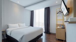 a bedroom with a white bed and a large window at Continent CentrePoint Makassar in Pampang +5 photos