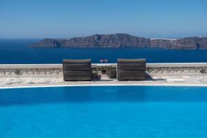 a swimming pool with two chairs next to the water at Xenones Filotera in Imerovigli +44 photos