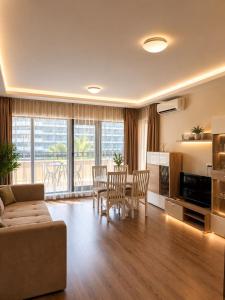 a living room with a couch and a table and chairs at ЛУКСОЗЕН АПАРТАМЕНТ В 4 звезден хотел in Golden Sands