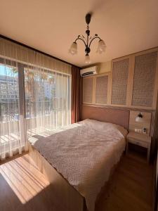a bedroom with a bed and a large window at ЛУКСОЗЕН АПАРТАМЕНТ В 4 звезден хотел in Golden Sands +20 photos