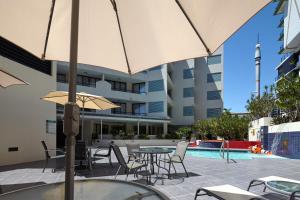 a patio with tables and chairs and an umbrella at West End Central Apartments in Brisbane