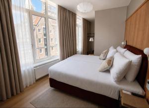 a bedroom with a bed and a large window at De Herbert Amsterdam - Formerly France Hotel in Amsterdam