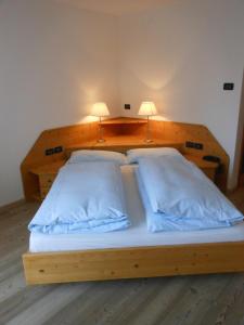 ein Holzbett mit zwei Lampen darüber in der Unterkunft Il Falchetto in Sarnonico