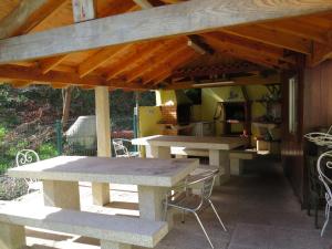 a picnic table and chairs under a wooden roof at Residência Iris in Geres