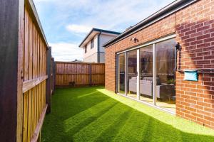 a backyard with a green lawn next to a brick building at Light-Filled Werribee Escape in Werribee