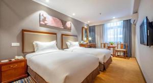 a hotel room with two beds and a television at Uniton Hotel Shenzhen in Shenzhen