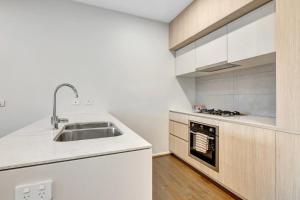 a white kitchen with a sink and a stove at Stylish 3-Bedroom Townhouse Near Shops & Parks in Point Cook