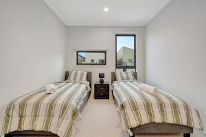 a bedroom with two beds and a mirror at Stylish 3-Bedroom Townhouse Near Shops & Parks in Point Cook