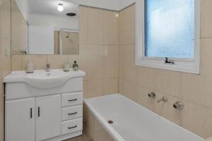 a white bathroom with a sink and a bath tub at Hoppers Crossing Hideaway Giant Backyard in Tarneit +16 photos