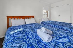 a blue and white bed with towels on it at Hoppers Crossing Hideaway Giant Backyard in Tarneit