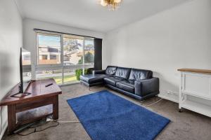 a living room with a leather couch and a blue rug at Hoppers Crossing Hideaway Giant Backyard in Tarneit