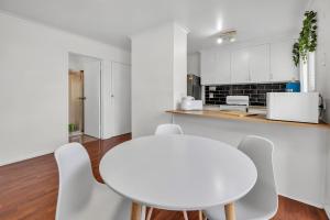 a white kitchen with a white table and chairs at Hoppers Crossing Hideaway Giant Backyard in Tarneit