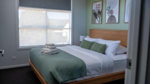 a bedroom with a large bed with a window and a bedskirtspectspectspects at Home Abroad in Ascot Park