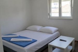 a bed with two pillows and a table and a window at M2 Apartmani in Trebinje +13 photos