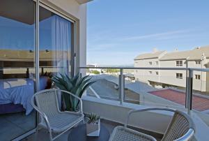 a balcony with two chairs and a bed at Blouberg Beach Escape in Cape Town