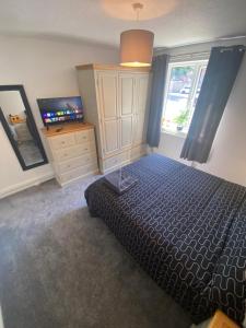a bedroom with a bed and a dresser and a television at 5 Star Large Double Room in Hull with Free Parking & WIFI in Anlaby