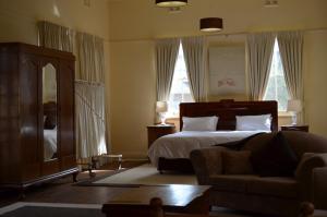 a bedroom with a bed and a couch and windows at Old Parkes Convent in Parkes