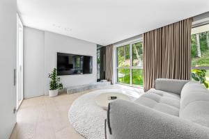 a living room with a couch and a tv at Refined luxury apartment surrounded by forest in Vilnius