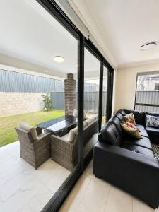 a living room with a black leather couch and a table at 4 Bedrooms Home in Gledswood Hills
