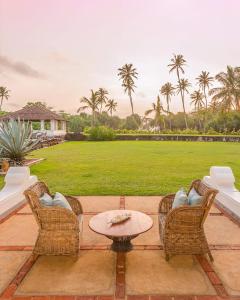 a patio with chairs and a table and a field at udesh hotel in Minuwangoda
