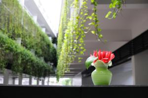 a green vase filled with red flowers on a table at Kasemsarn Hotel Chanthaburi in Chanthaburi