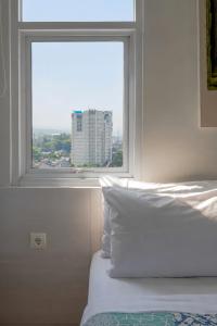 a bedroom with a window with a view of a building at Dago Suite 3BR Luxury Apartment in Bandung