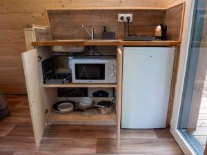 a small kitchen with a microwave and a refrigerator at La cabane en A 