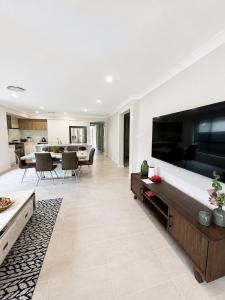 a living room with a large television and a dining room at 4 Bedrooms Home in Gledswood Hills