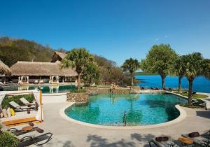 a pool at a resort with the ocean in the background at Secrets Papagayo All Inclusive - Adults Only in Papagayo, Guanacaste