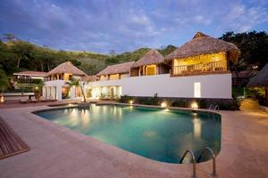 a villa with a swimming pool in front of a house at Secrets Papagayo All Inclusive - Adults Only in Culebra