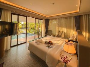 a bedroom with a bed and a television and a pool at Riahi Villas by Swiss-Belhotel, Nirup Island in Belakangpandang +66 photos
