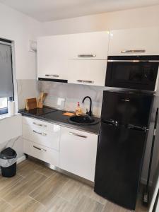 a kitchen with a black refrigerator and white cabinets at Terra Residence Beiuș in Beiuş +6 photos