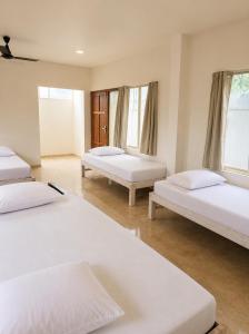 a room with three beds and two windows at Vedic villa Cherai beach in Cochin +5 photos