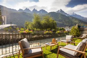 a patio with chairs and a table and mountains at Hôtel de L'Arve by HappyCulture in Chamonix
