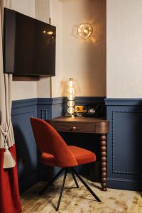 a red chair sitting next to a desk with a television at Château du Portereau in Vertou