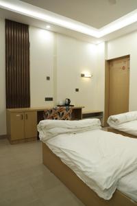 a bedroom with two beds and a desk with a chair at Shree Krishna Hotel & Restraunt in Pātolī +26 photos