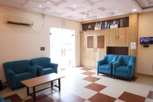 a waiting room with blue chairs and a table at Shree Krishna Hotel & Restraunt in Pātolī