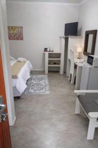 a bedroom with a bed and a desk and a computer at The Courtyard Guesthouse in Matola