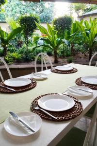 a table with plates and utensils on it at The Courtyard Guesthouse in Matola +4 photos
