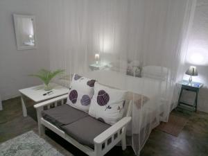 a white room with a table and a bench with pillows at The Courtyard Guesthouse in Matola