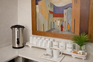 a counter with cups and a painting on the wall at The Courtyard Guesthouse in Matola