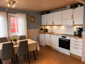 a kitchen with white cabinets and a table with chairs at Rønsholmen brygger in Beian