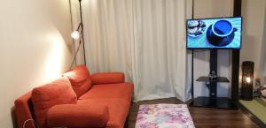 a living room with an orange couch and a flat screen tv at ARASHIMA INN 201 / Vacation STAY 162 in Toba
