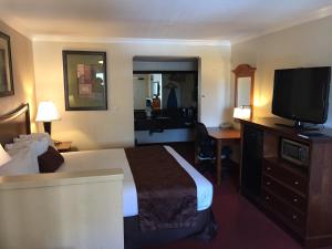 a hotel room with a bed and a flat screen tv at Chula Vista Inn in Chula Vista